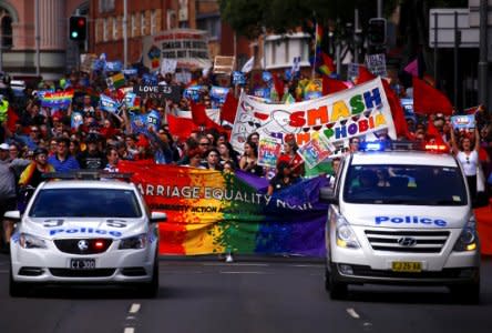 Police drive in front of marchers holding signs and banners as they participate in a marriage equality march in central Sydney, Australia, October 21, 2017.      REUTERS/David Gray