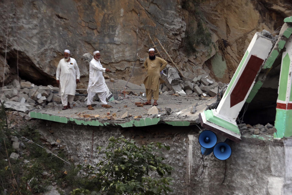 People stand inside of the damaged mosque after a suicide bomber attack inside a roadside mosque in the Khyber district in Khyber Pakhtunkhwa province, of Pakistan, Tuesday, , July 25, 2023. A suicide bomber blew himself up inside a roadside mosque when a police officer tried to arrest him after a chase in northwestern Pakistan near the Afghan border on Tuesday, killing the officer, police said. (AP Photo/Muhammad Sajjad)