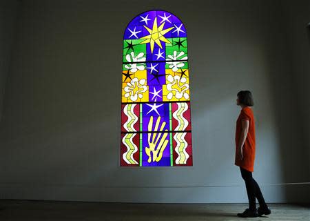 An employee poses with a stained glass "Christmas Eve" (Nuit de Noel), designed by Henri Matisse, and in collaboration with Paul Bony, at the Tate Modern gallery in London April 14, 2014. REUTERS/Luke MacGregor