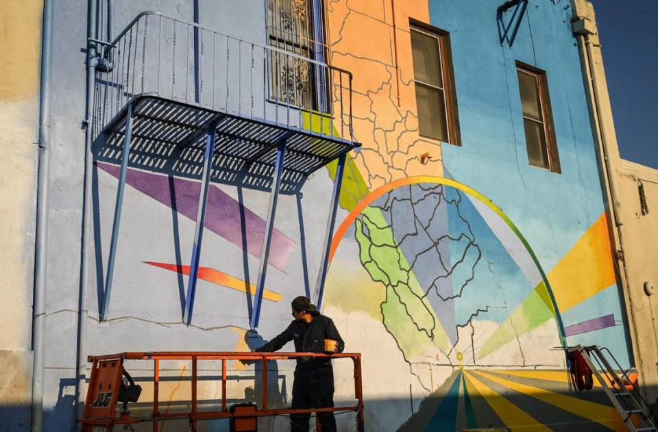 Fresno muralist Mauro Carrera works on a mural on a historic Chinatown building on China Alley in downtown Fresno on Friday, Dec. 16, 2022. The project is in conjunction with the Fresno Arts Council and the California High-Speed Rail Authority.