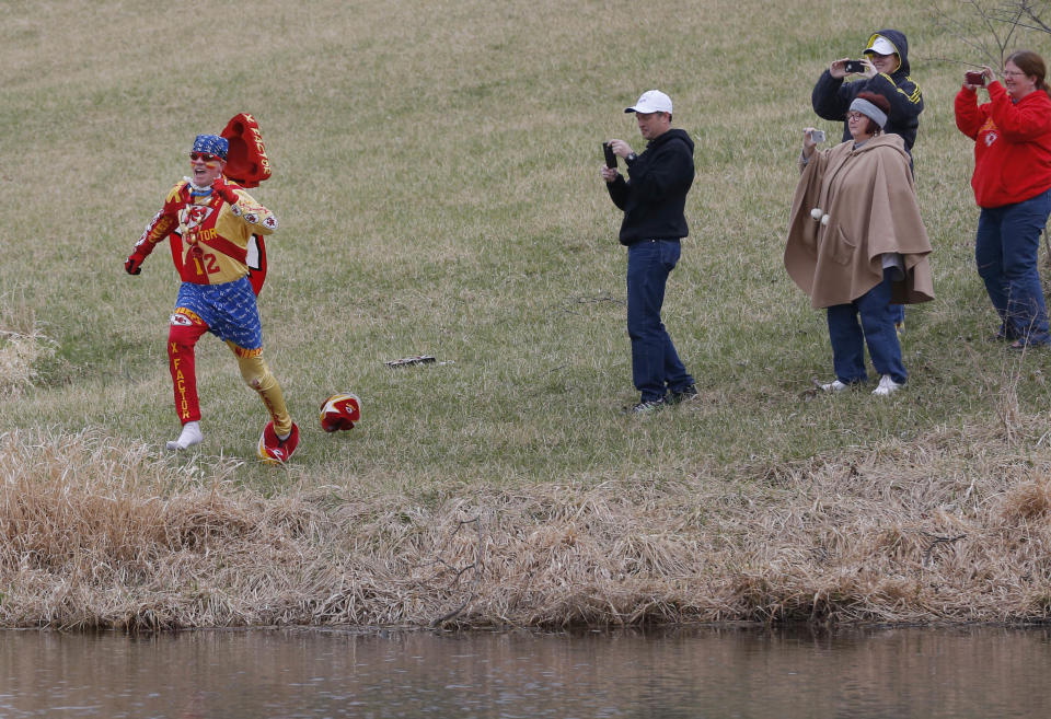 Kansas City Chiefs fan Ty Rowton, known as XFactor, is videoed by friends as he takes a Plunge for Landon in a farm pond near Bonner Springs, Kan., Friday, April 4, 2014. A 5-month-old boy's battle with cancer has inspired hundreds to jump into cold bodies of water, from a local golf course pond to the Gulf of Mexico and even the Potomac River in Washington, D.C. (AP Photo/Orlin Wagner)