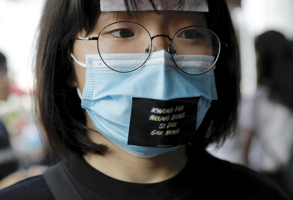 A woman wears a face mask and a sticker reading "Add oil Hong Kong people" during a demonstration at Edinburgh Place in Hong Kong, Thursday, Aug. 22, 2019. High school students thronged a square in downtown Hong Kong Thursday to debate political reforms as residents gird for further anti-government protests. (AP Photo/Vincent Yu)