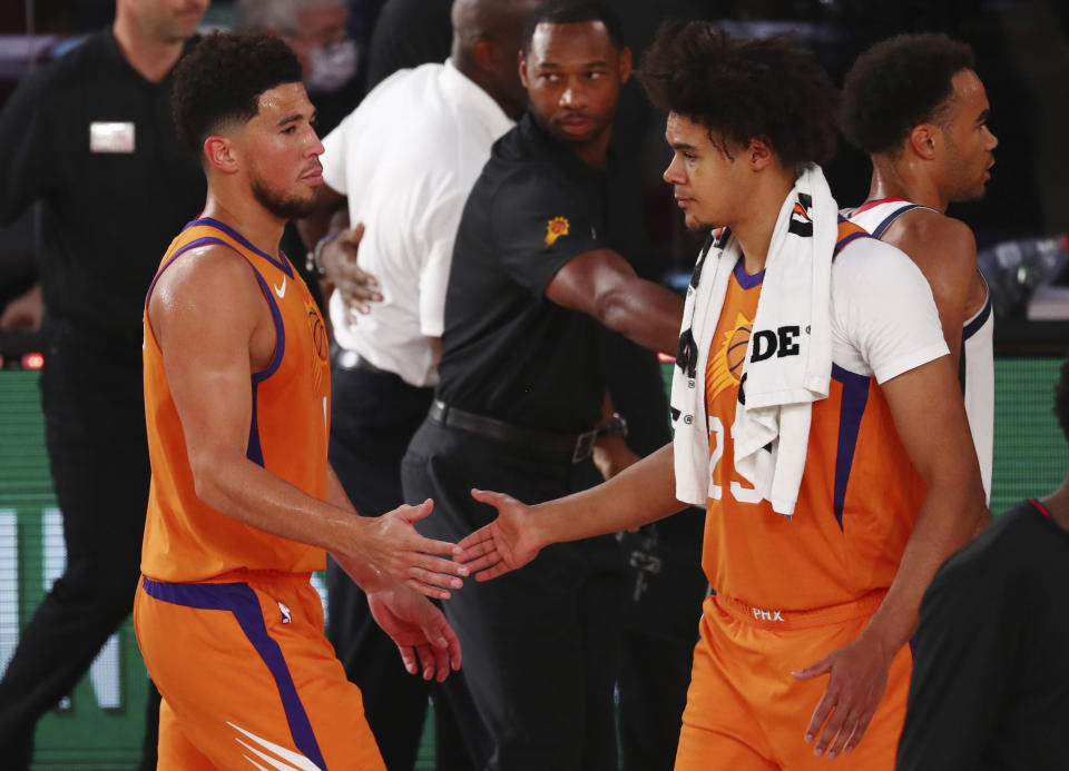 Phoenix Suns guard Devin Booker (1) slaps hands with forward Cameron Johnson (23) after defeating the Washington Wizards in an NBA basketball game in Lake Buena Vista, Fla., Friday, July 31, 2020. (Kim Klement/Pool Photo via AP)