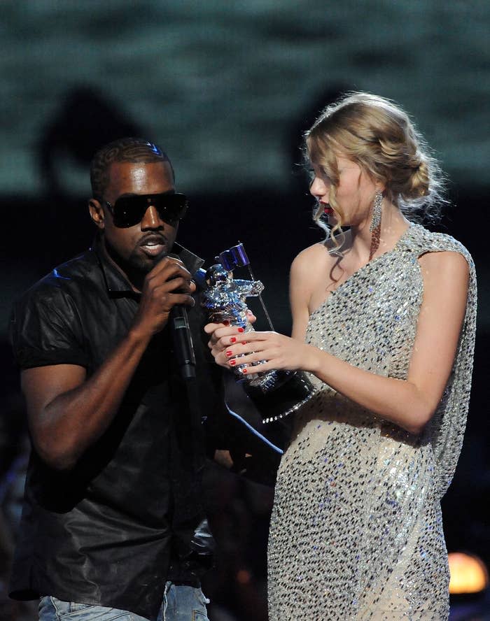 Ye holding the mic onstage with Taylor, who's holding an award