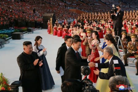 North Korean leader Kim Jong Un and wife Ri Sol Ju look on as China's President Xi Jinping and his wife Peng Liyuan are greeted by performers at a mass display during Xi's visit in Pyongyang, North Korea in this undated KCNA photo