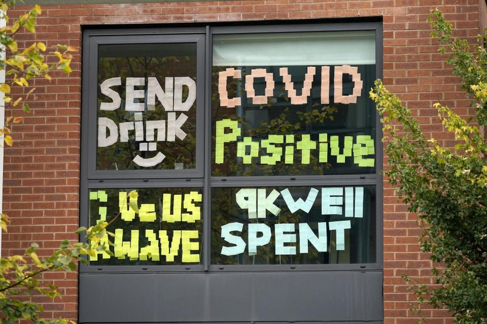 Signs made by students are displayed in a window of their locked down accommodation building in Manchester (Getty Images)