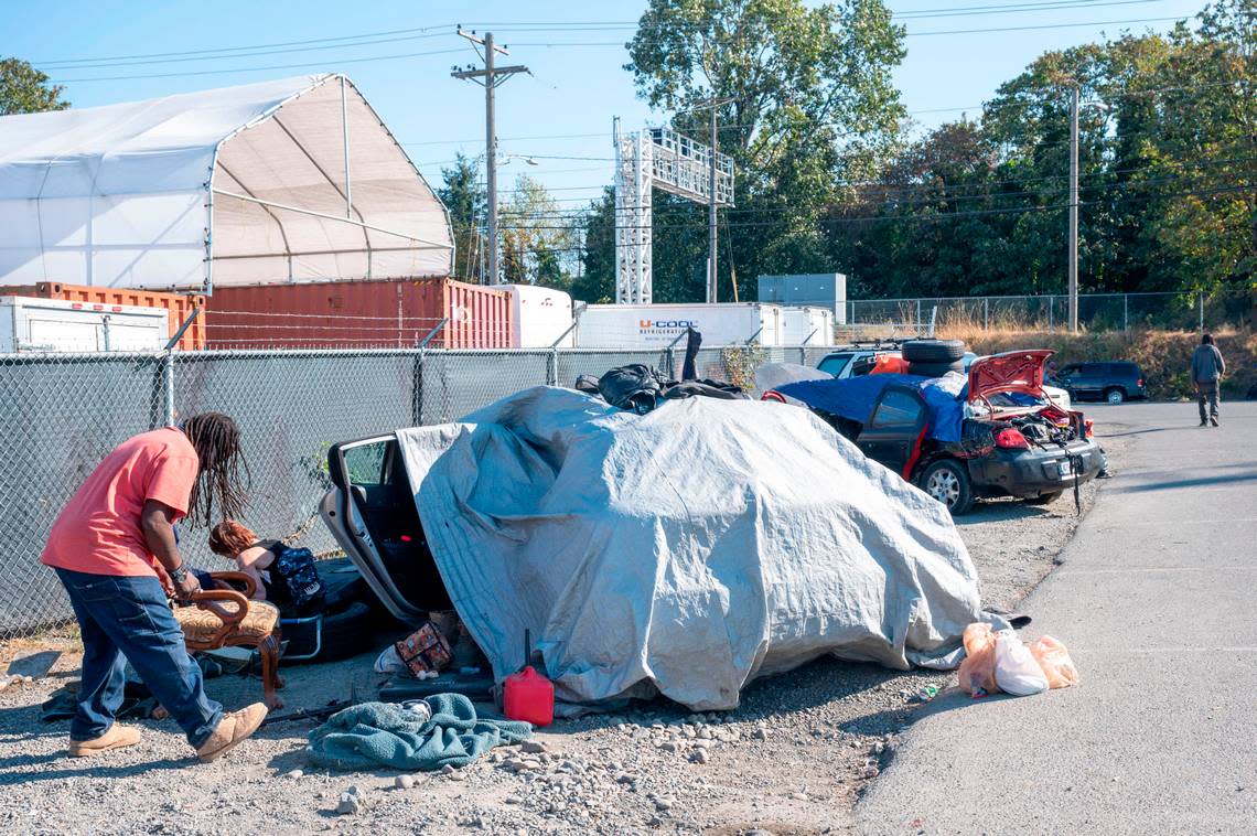 Wolf (left), who asked not to use his last name, cleans up around his car where he is living out of along M Street near the 1200 block of Puyallup Avenue in Tacoma on Sept. 20, 2022. This week the Tacoma City Council passed an ordinance that prohibits camping in a 10-block radius around public property where temporary shelters are located.