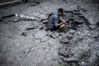 A Ukrainian man videos a shell crater in Donetsk, on July 29, 2014