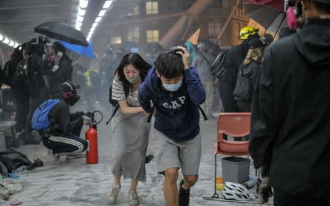 Protesters run for cover after riot police fired tear gas towards the bridge they were climbing down to the road below - Credit: Anthony WALLACE / AFP