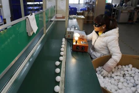 An employee tests newly-made light bulbs along a production line of a factory in Jiaxing, Zhejiang province February 6, 2015. REUTERS/William Hong