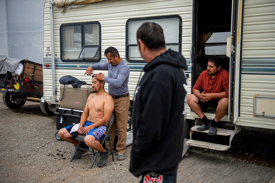 Julio Hernandez cuts the hair of his brother, Alvaro Hernandez, at a farm that opened space to people displaced by wildfires in Central Point, Ore., on Sept. 26, 2020. The Almeda Fire leveled some of the only affordable housing for the immigrants who work the fields, kitchens and construction sites of southern Oregon.<span class="copyright">Amanda Lucier—The New York Times/Redux</span>