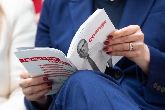 A woman reads a copy of the Labour manifesto