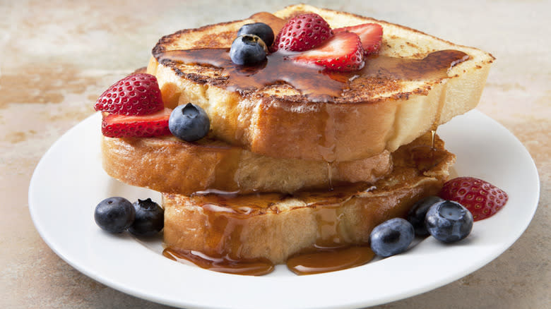 French toast on a plate with fruit and syrup