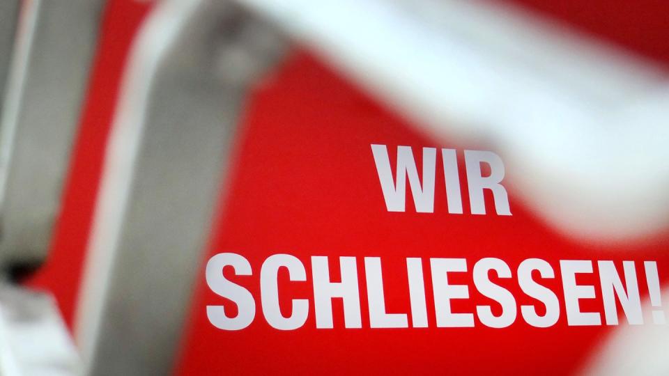 Der Schriftzug «Wir schließen!» steht hinter einem Rollgitter an einem geschlossenen Geschäft.