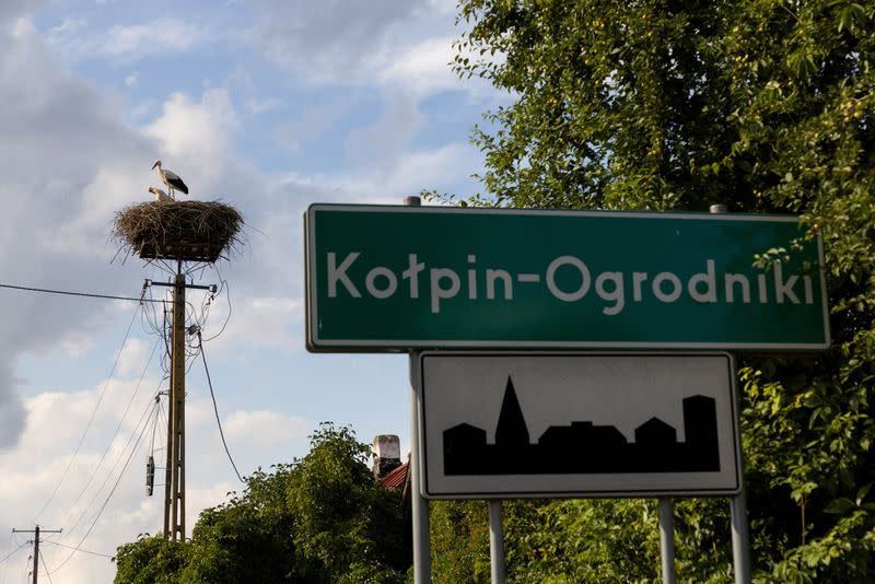 Storks nest near a village sign, in Kolpin-Ogrodniki