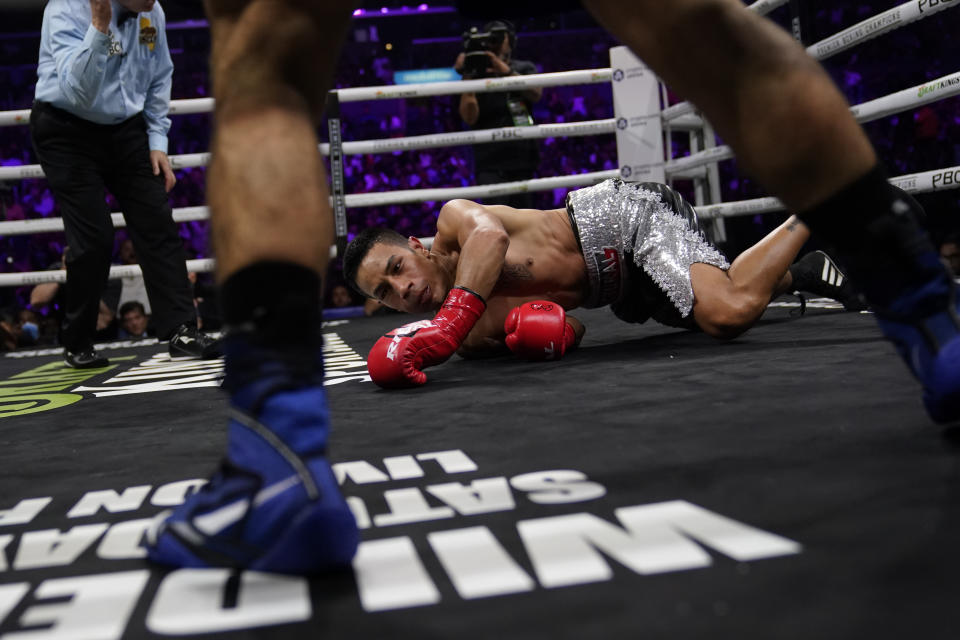 Eduardo Ramirez, center, is knocked down by Isaac Cruz in a WBC world lightweight title eliminator boxing match, Sunday, Sept. 4, 2022, in Los Angeles. (AP Photo/Ashley Landis)