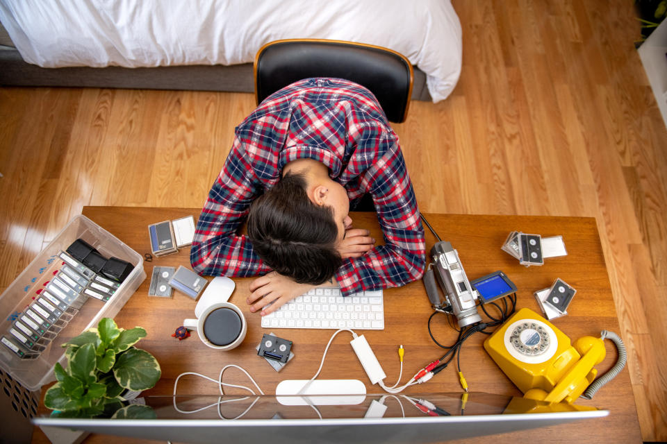 Person slumped over their desk while editing movies in their home office