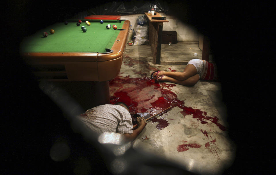 FILE - This March 11, 2012 file photo show the bodies of Lesbia Altamirano and Wilmer Orbera on the bloody floor of a pool hall after being attacked by masked assailants in Choloma, on the outskirts of San Pedro Sula, Honduras. During President Porfirio “Pepe” Lobo Sosa's 2010-2013 administration, Honduras had deteriorated into violent upheaval. In 2011, the U.N. ranked it as the country with the world’s highest murder rate. The U.S. State Department described it as “primary transshipment point” for U.S.-bound cocaine. (AP Photo/Esteban Felix, File)