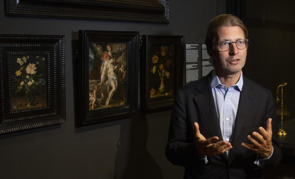 Rijksmuseum director Taco Dibbits, standing in front of Bartholomeus Spanger's "Body of Christ Supported by Angels" oil on copper painting, center, discusses the gift of the major painting the cultural institution received to underscore support for the victims of the coronavirus pandemic and the crisis that museums face world wide, which went on display in Amsterdam, Netherlands, Monday, June 1, 2020. The Dutch government took a major step to relax the coronavirus lockdown, with bars, restaurants, cinemas and museums reopening under strict conditions. (AP Photo/Peter Dejong)