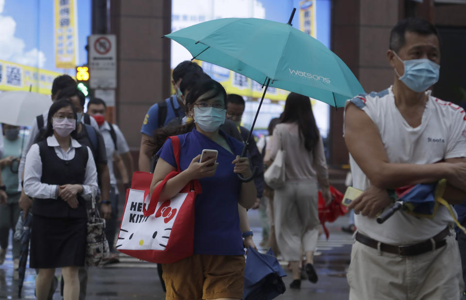 People wear face masks to protect against the spread of the coronavirus and walk in the light rain from approaching Typhoon In-Fa in Taipei, Taiwan, Thursday, July 22, 2021. (AP Photo/Chiang Ying-ying)