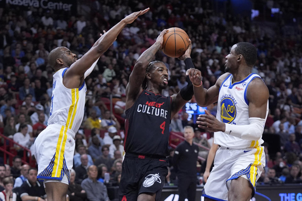 Miami Heat guard Delon Wright (4) looks for an opening past Golden State Warriors guard Chris Paul, left, and forward Jonathan Kuminga during the first half of an NBA basketball game, Tuesday, March 26, 2024, in Miami. (AP Photo/Wilfredo Lee)