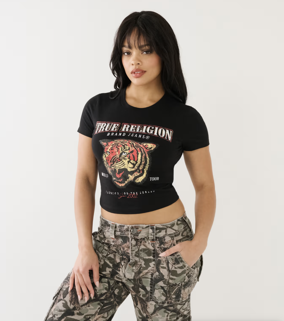 model wearing black tee with tiger graphic and camo pants