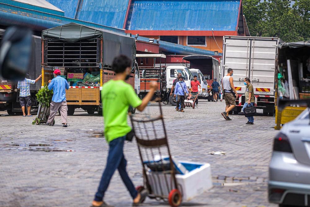 Workers are seen unloading fresh produce from trucks at the Kuala Lumpur Wholesale Market in Selayang June 24, 2020. — Picture by Hari Anggara