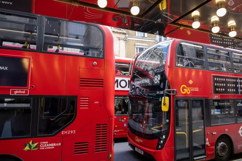 Red London double decker buses reflected in the mirror ceiling outside a theatre