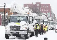 Power line trucks arrive on Allen Street to supply power to apartments and homes in Buffalo, N.Y., on Monday, Dec. 26, 2022. Many people lost power where they live due to the recent blizzard. (Joseph Cooke/The Buffalo News via AP)