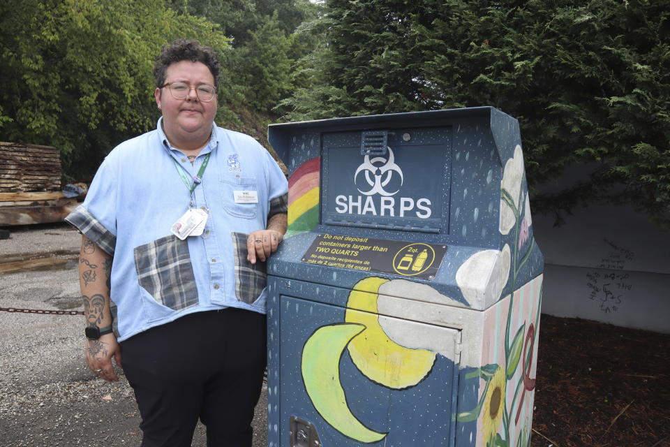 Iris Sidikman, harm reduction coordinator at the Women’s Health Center of West Virginia, poses for a portrait beside a syringe disposal box in the clinic parking lot on Thursday, August 4, 2023, in Charleston, W.Va. (AP Photo/Leah Willingham)