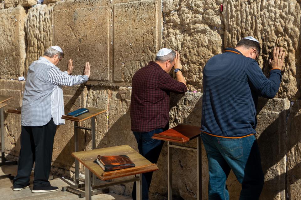 Three people pray as they touch a part of the Western Wall inside JerusalemÕs Old City.