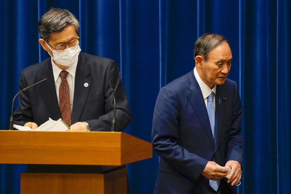 FILE - In this Aug. 17, 2021, file photo, Japanese Prime Minister Yoshihide Suga, right, walks past Shigeru Omi, chairman of the government's pandemic advisory panel, after a news conference at prime minister's official residence in Tokyo. Suga announced on Aug. 17, 2021, a decision to expand and extend a state-of-emergency covering Tokyo and other areas until at least mid-September, although most of the restrictions aren't legally enforceable. (Kimimasa Mayama/Pool via AP, File)