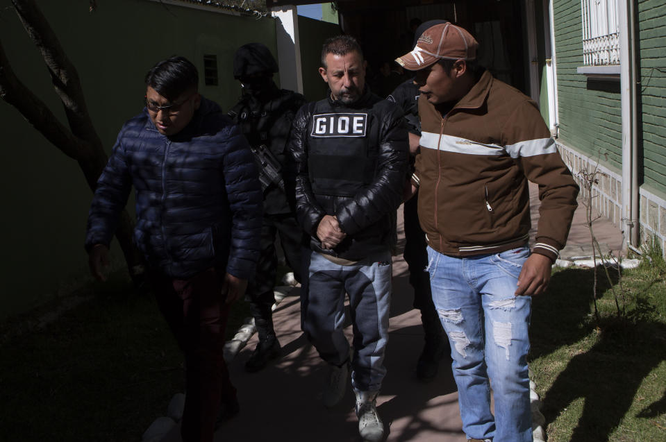 Alleged drug kingpin Paolo Lumia, wearing a bulletproof vest, center, is escorted to a waiting vehicle by anti-drug officers, after a media presentation in La Paz, Bolivia, Thursday, July 4, 2019. Authorities in Bolivia arrested Lumia in the Bolivian city of Cochabamba on Wednesday night. There is an international arrest warrant out for the Italian citizen. (AP Photo/Juan Karita)