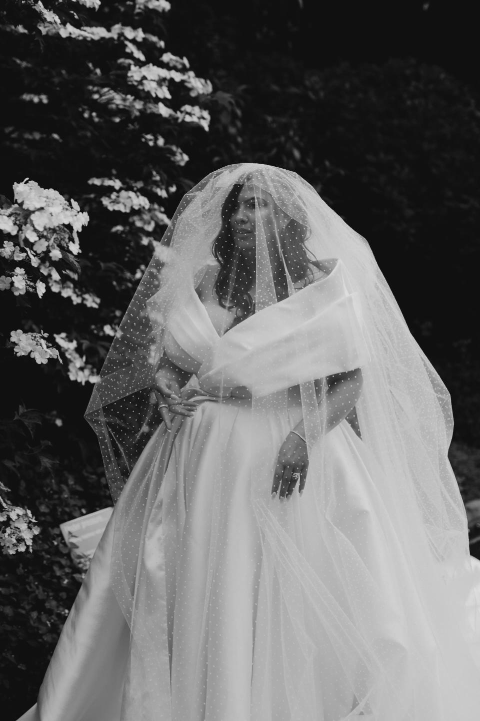 A black-and-white photo of a bride in her wedding dress covered in a veil.