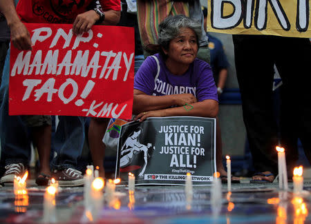 Protesters hold placards seeking justice for 17-year-old high school student Kian delos Santos, who was killed in a recent police raid, during a candlelight protest in front of the Philippine National Police (PNP) headquarters in Quezon city, Metro Manila, Philippines August 23, 2017. The placard on the left reads "Philippine National Police (PNP) Killers". REUTERS/Romeo Ranoco