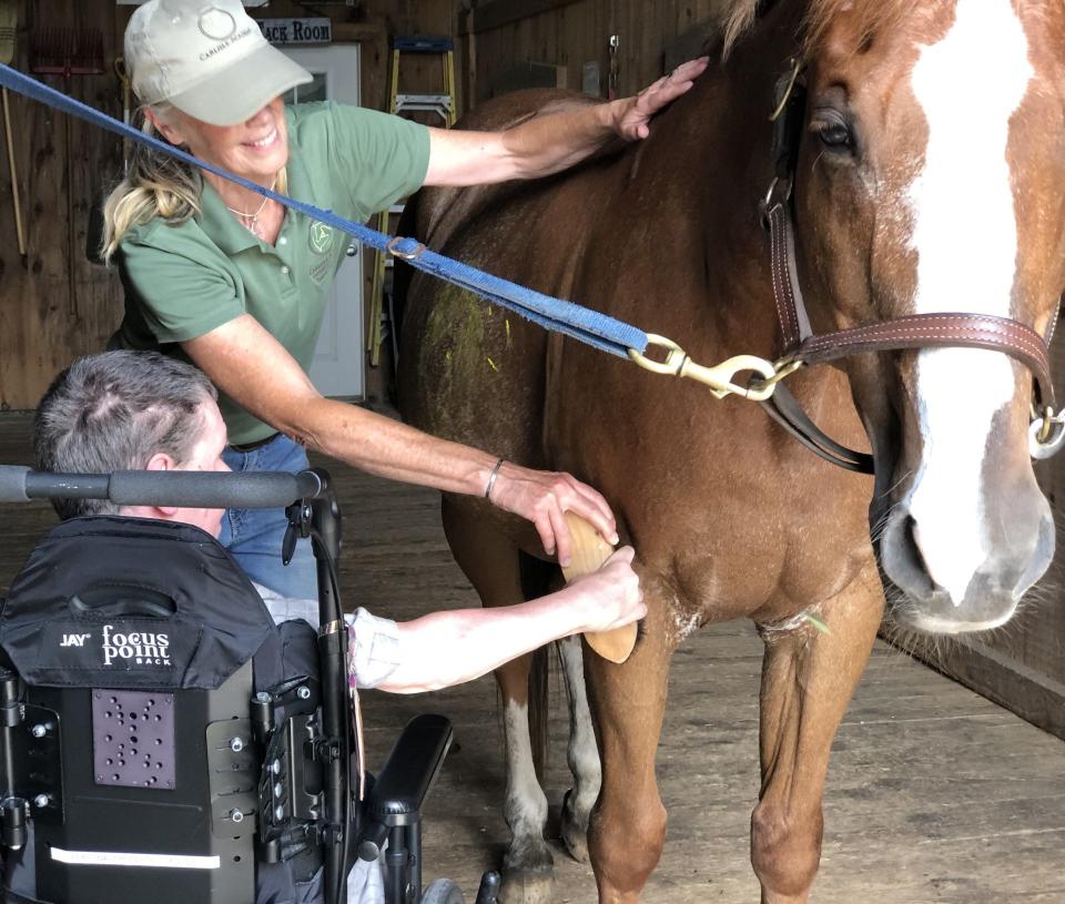 Joyce Brown helps a resident of the RiverRidge Center brush Keeker the Horse at Carlisle Academy in Lyman, Maine, on July 13, 2023.