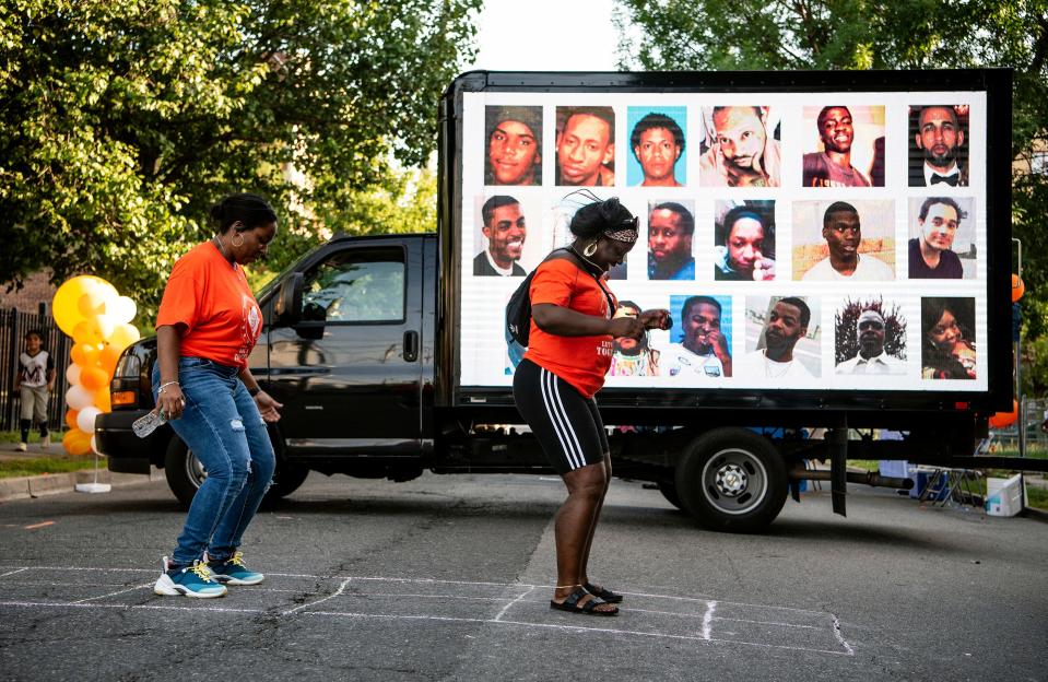 1st Ward WINS members Tiffany Jacobs and Kimmeshia Rogers-Jones, a lifelong resident of the 1st Ward, hopscotch in front of a truck displaying recent victims of gun violence in Paterson during a block party on June 5, 2021. The group partnered with the Paterson Healing Collective during the "Healing Fest," to host a block party on N. Main St. and Arch St., a block prone to gun violence. The festival coincided with "Wear Orange," weekend, a national effort dedicated to bring awareness to gun violence.