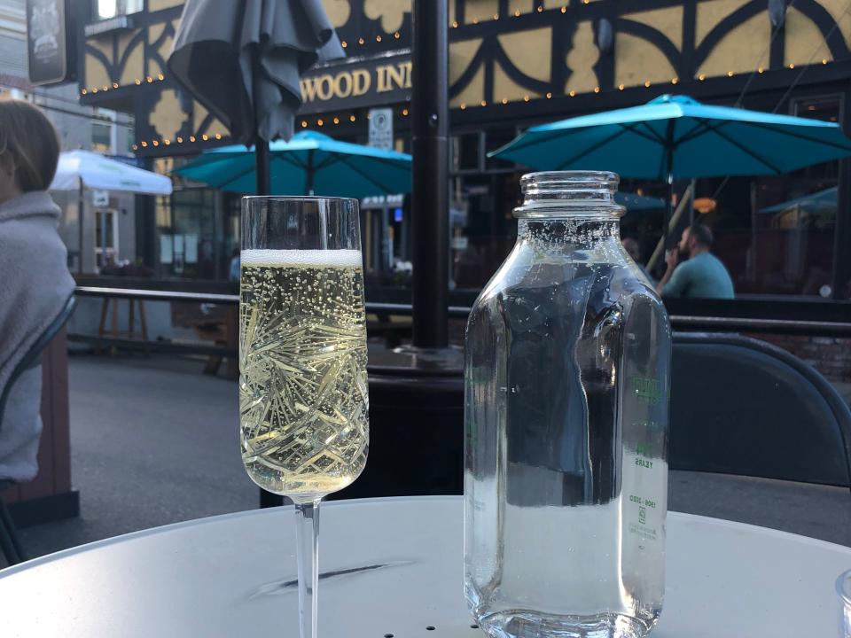 glass of sparkling wine and a jug of water on a table at a cafe in fernwood square in victoria bc