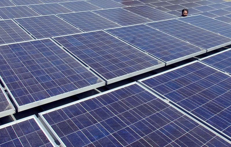 FILE PHOTO: A man views solar panels on a roof at Google headquarters in Mountain View