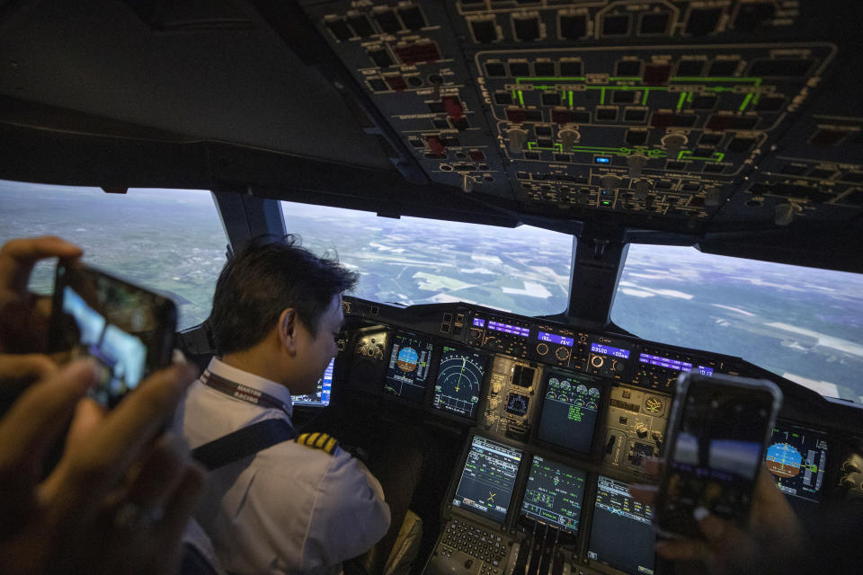 Customers take video with mobile phones as Captain Chaisupatt Mulsrikaew shows how to control flight in a Boeing A380 flight simulator at the Thai Airways head office in Bangkok, Thailand on Oct. 3, 2020. The airline is selling time on its flight simulators to wannabe pilots while its catering division is serving meals in a flight-themed restaurant complete with airline seats and attentive cabin crew. The airline is trying to boost staff morale, polish its image and bring in a few pennies, even as it juggles preparing to resume international flights while devising a business reorganization plan. (AP Photo/Sakchai Lalit)