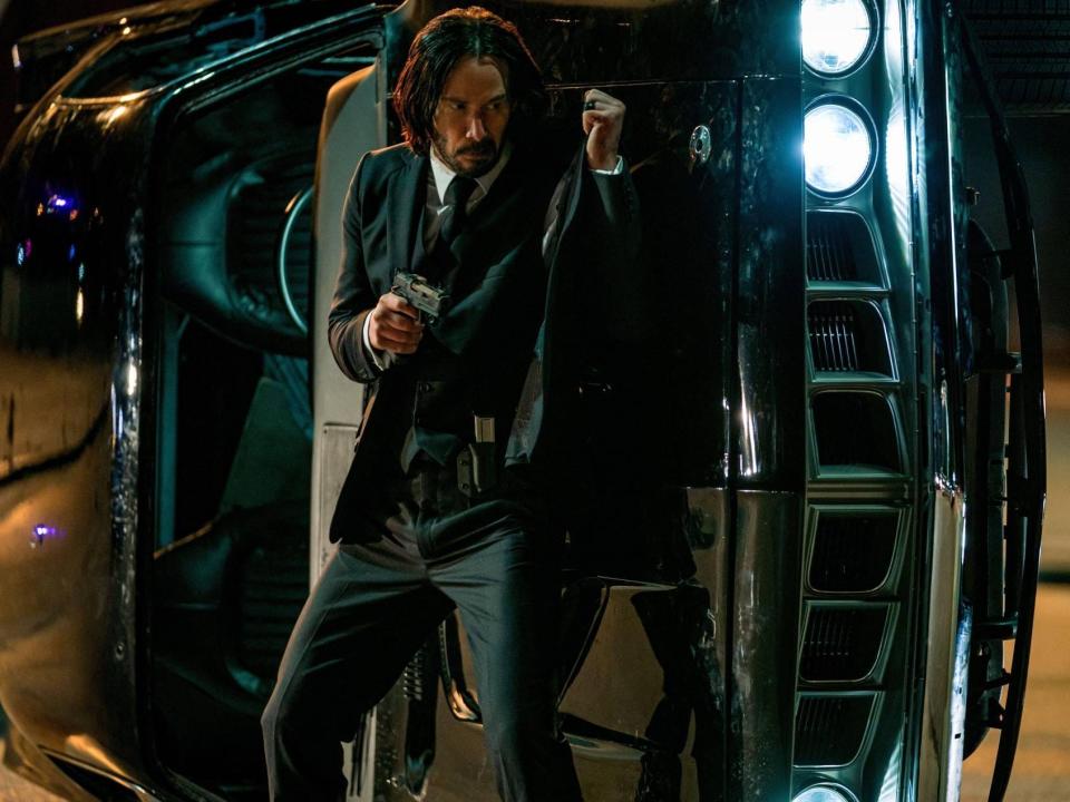 Keanu Reeves as John Wick holding up his bullet proof jacket.