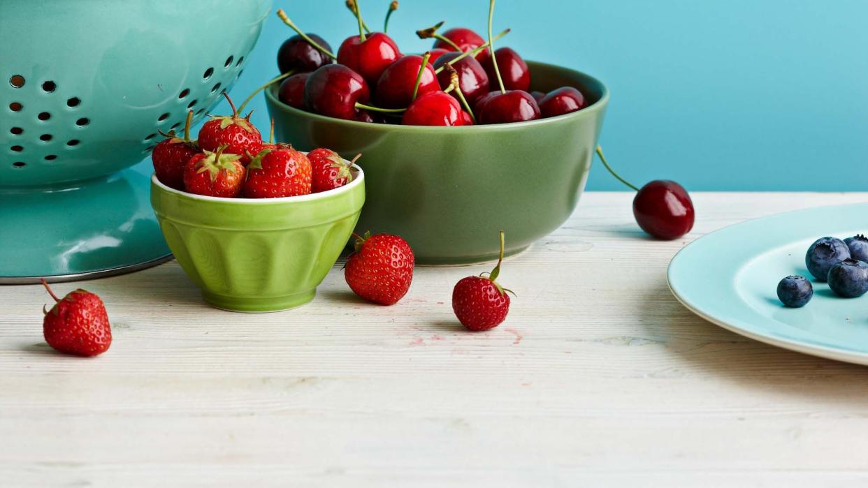 apples, cherries, strawberries, and blueberries in bowls on a table