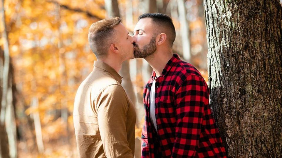 two men kissing in the woods