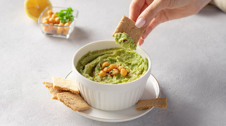 Avocado herb hummus with hand