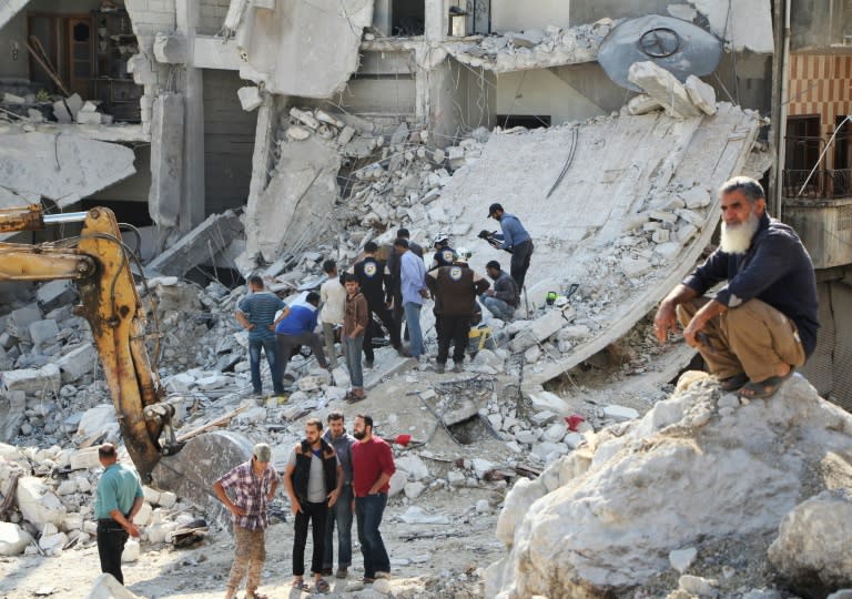 Syrian civil defence volunteers (C) search for victims amid the rubble of destroyed buildings on October 24, 2016, following overnight air strikes in the rebel-held town of Kafar Takharim, in Idlib province of northwest Syria