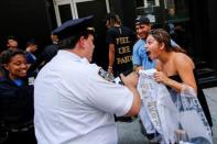 A shopper shows her "The Life of Pablo" merch to NYPD officers after visiting a pop up store featuring fashion by Kanye West in Manhattan, New York, U.S., August 19, 2016. REUTERS/Eduardo Munoz