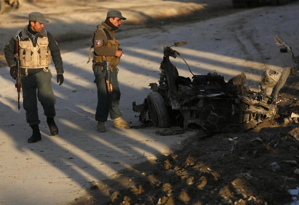 Afghan policemen look at the wreckage of a suicide bomber's car at the site of an attack in Kabul