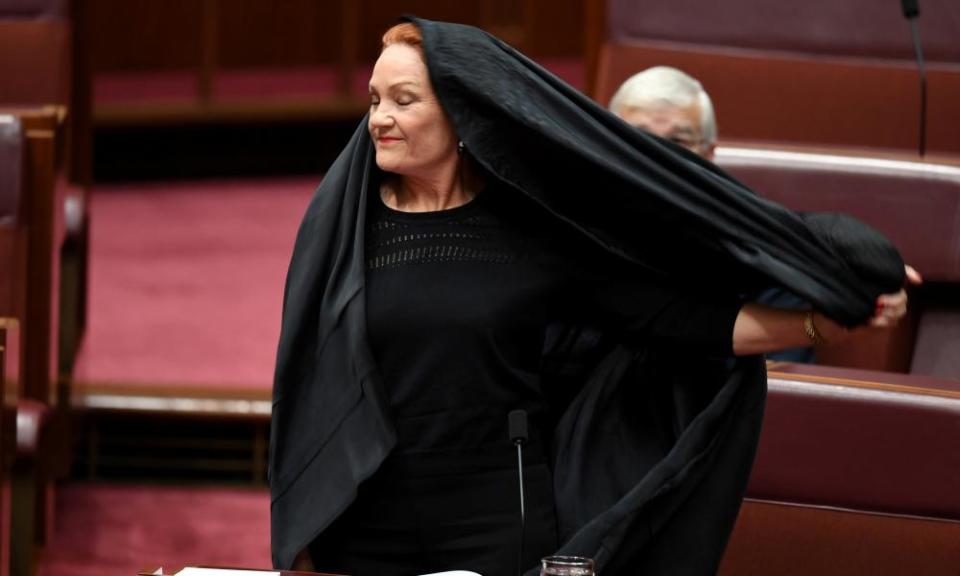 One Nation leader Pauline Hanson pulls off the burqa she wore to question time in the Senate chamber.