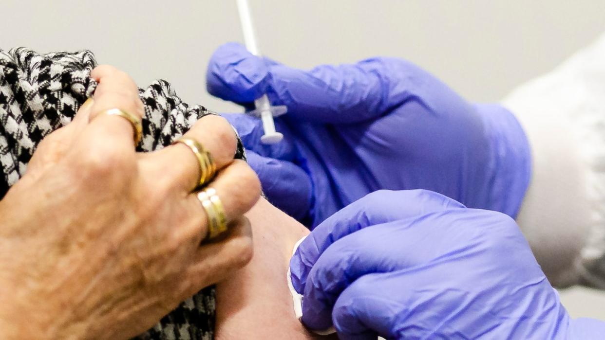 Die Einstichstelle am Arm einer Frau in Kiel wird nach dem Impfen desinfiziert.