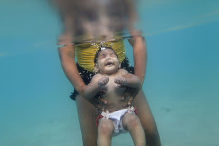 Rosana Vieira Alves and her five-month-old daughter Luana Vieira, who was born with microcephaly, pose for a picture in the sea of Porto de Galinhas, a beach located in Ipojuca, in the state of Pernambuco, Brazil, March 2, 2016. REUTERS/Ueslei Marcelino/File Photo